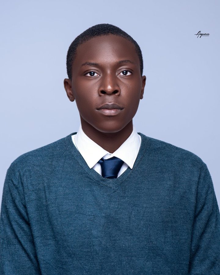 Ayo Osota in a green sweater and tie, looking at the camera